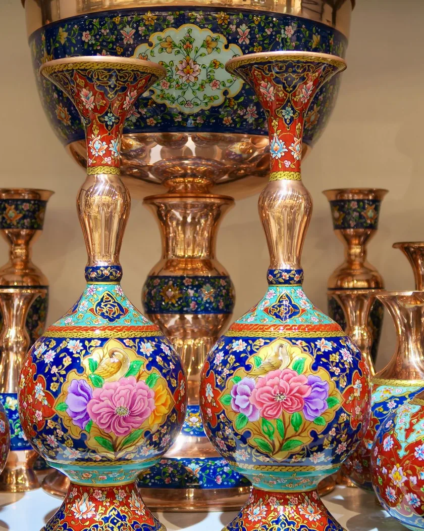Piezas de cobre esmaltadas con motivos florales en azul, rojo y verde, con partes de metal a la vista